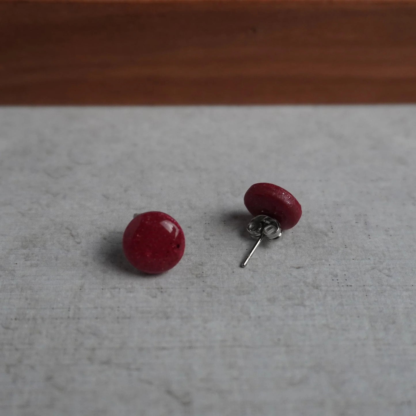 Kleine glitzernde runde Ohrringe (Red Velvet) liegend